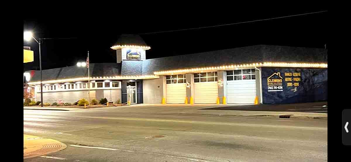 Indiana commercial shop front lit with warm white Christmas lights along the roofline at night